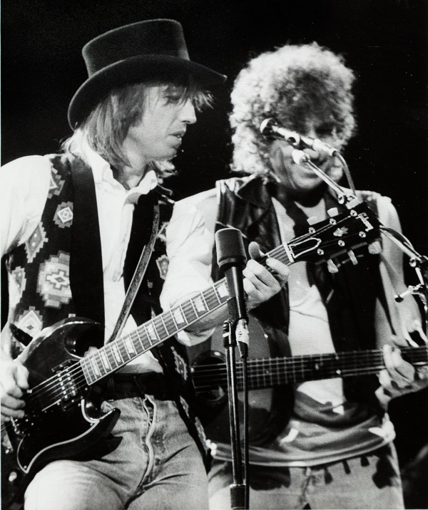 Tom Petty playing the guitar on stage with Bob Dylan in 1987 