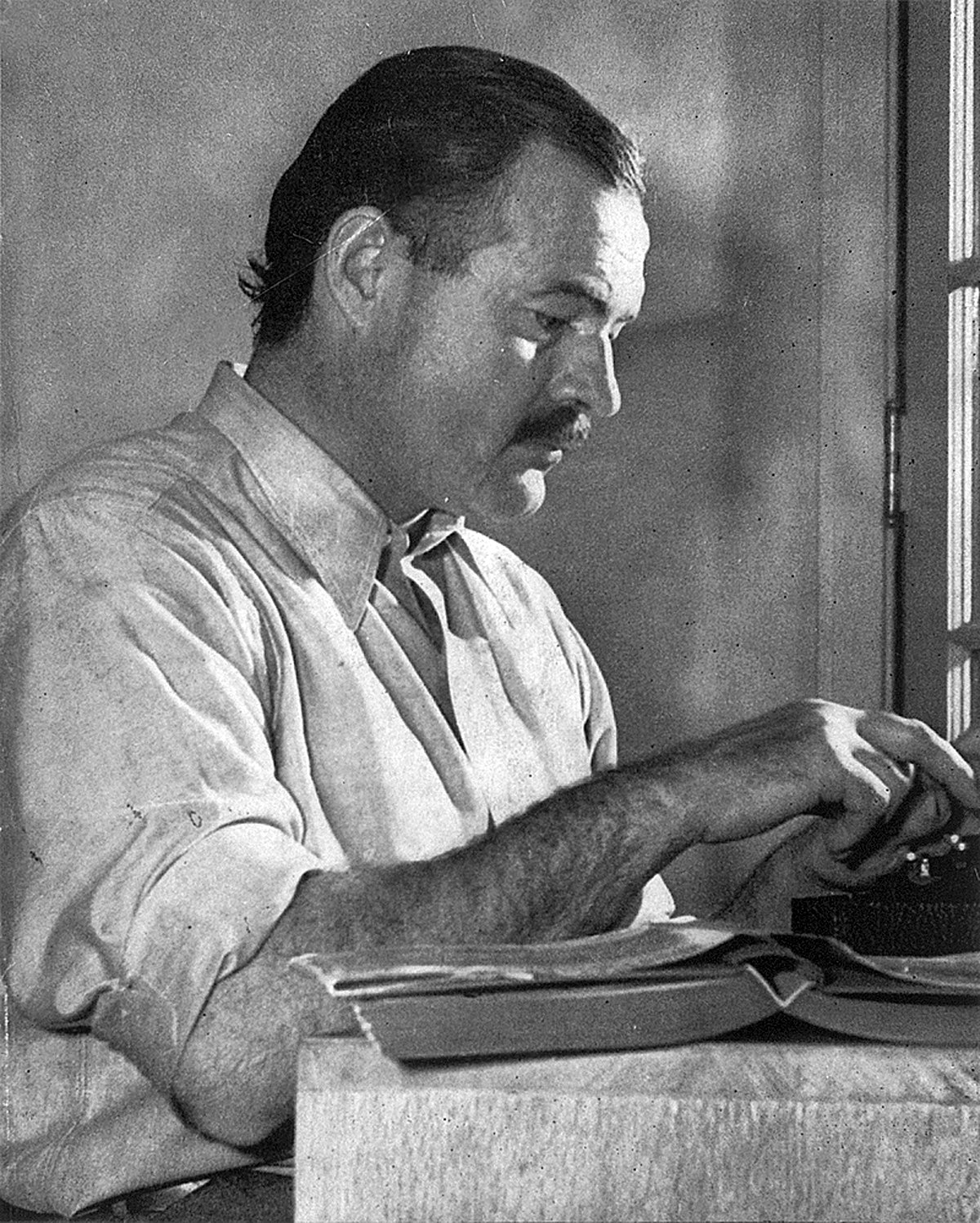Ernest Hemmingway writing at a typewriter.