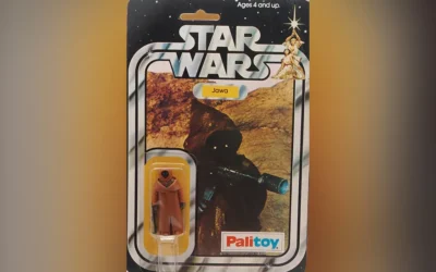 A Star Wars figure of a Jawa in a vinyl cape in its original packaging.
