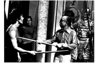 Bruce Lee filming with a bo staff.