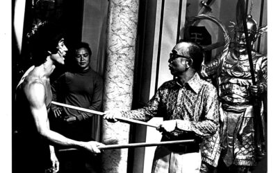 Bruce Lee filming with a bo staff.