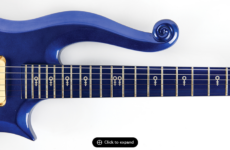 Blue Prince Cloud guitar from 1985's Purple Rain Movie. Image shows a section of the guitar body with a curled upper horn and a neck with symbols.