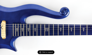 Blue Prince Cloud guitar from 1985's Purple Rain Movie. Image shows a section of the guitar body with a curled upper horn and a neck with symbols.