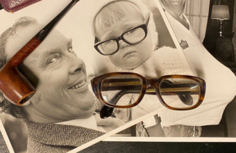 A pair of Eric Morecambe's trademark glasses with photographs and pipe.