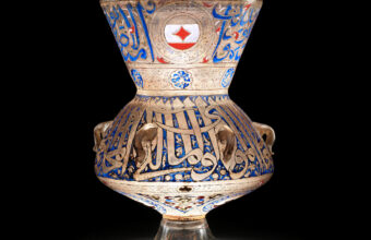 A glass, enamel and gilted mosque lamp sold for over £5 million is seen glowing against a black backdrop.