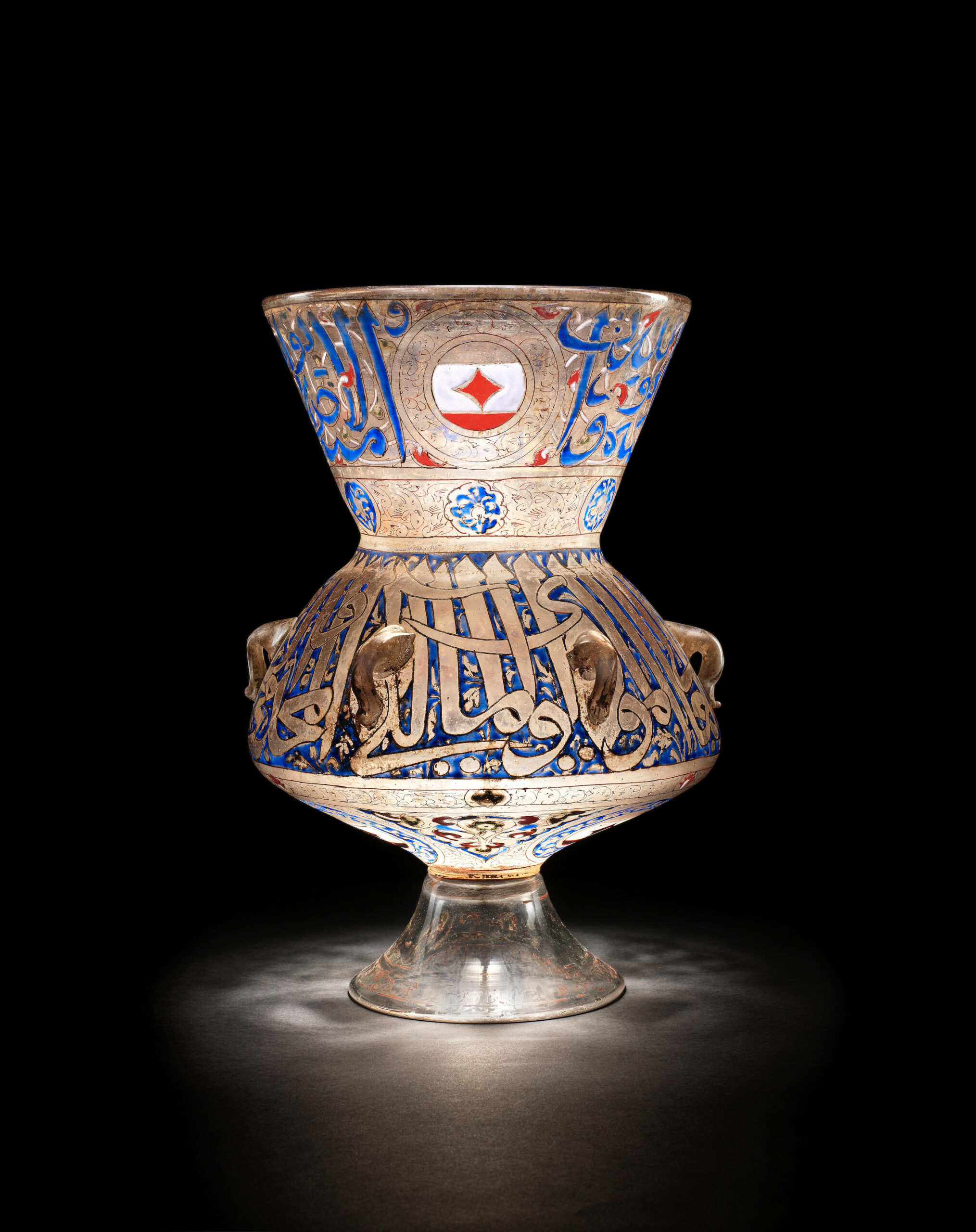 A glass, enamel and gilted mosque lamp sold for over £5 million is seen glowing against a black backdrop.