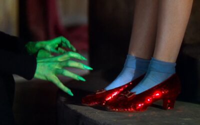 Judy Garland as Dorothy Gale wears Ruby Slippers in the Wizard of Oz. Here, the green hands of the Wicked Witch of the West can be seen grasping for them.