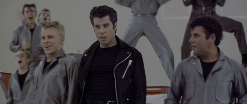 John Travolta as Danny Zuko singing Greased Lightinin with the T Birds in Grease