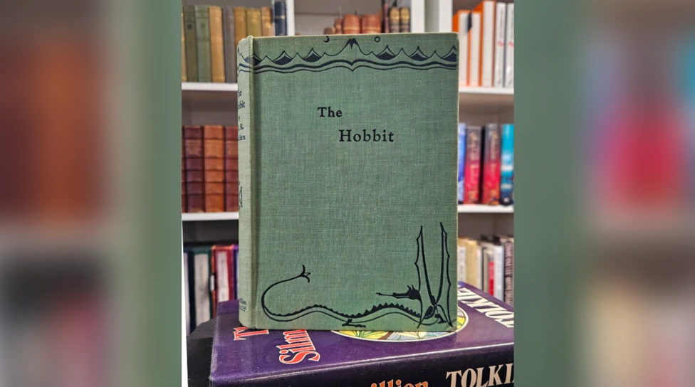 First edition copy of the Hobbit by JRR Tolkien, photographed standing upright amid other books. Copy has no dust jacket.