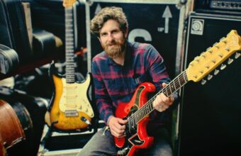 An auctioneer demonstrates a Burns Six on Six 12-string guitar once owned by Mark Knopfler that is being sold at auction.