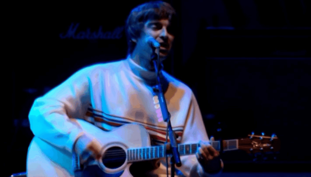 Noel Gallagher of Oasis playing a takemime acoustic guitar on stage 