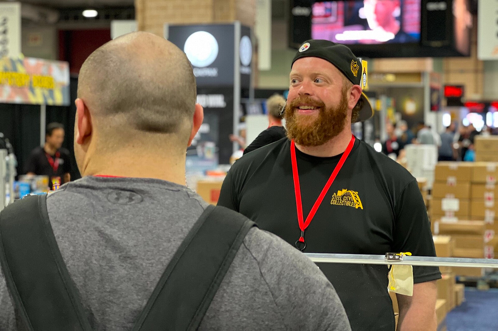A collectibles dealer speaking with a customer at a sports card convention