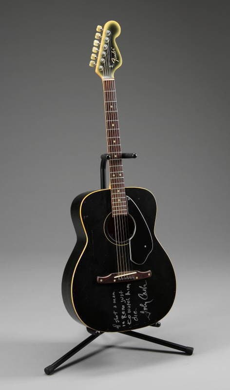 Black Fender acoustic guitar featuring handwritten lyrics on the body
