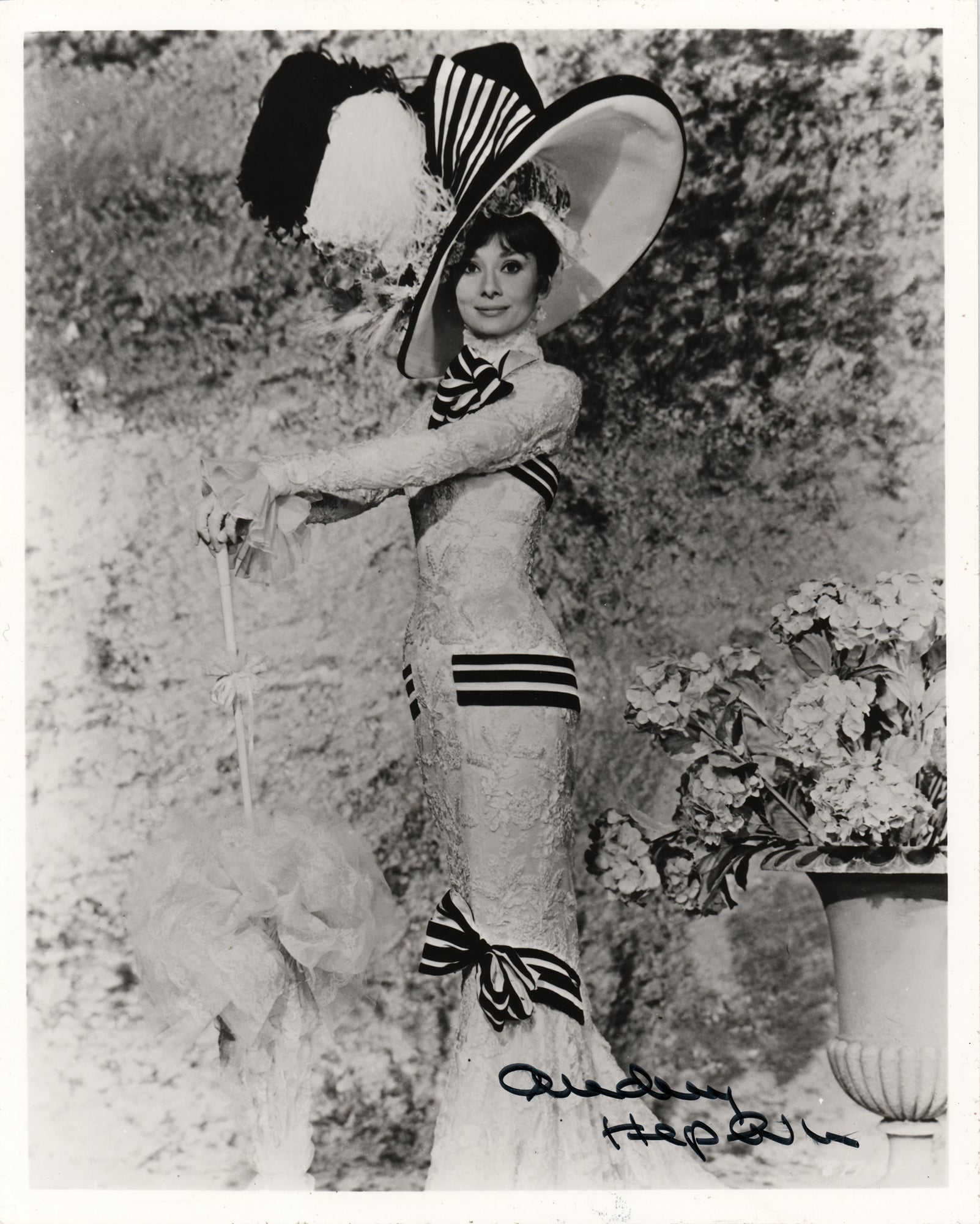 Audrey Hepburn wore a white lace and black-striped Ascot dress as Eliza Doolittle in the 1964 film My Fair Lady. The Edwardian-style monochrome gown and feathered hat were designed by Cecil Beaton.