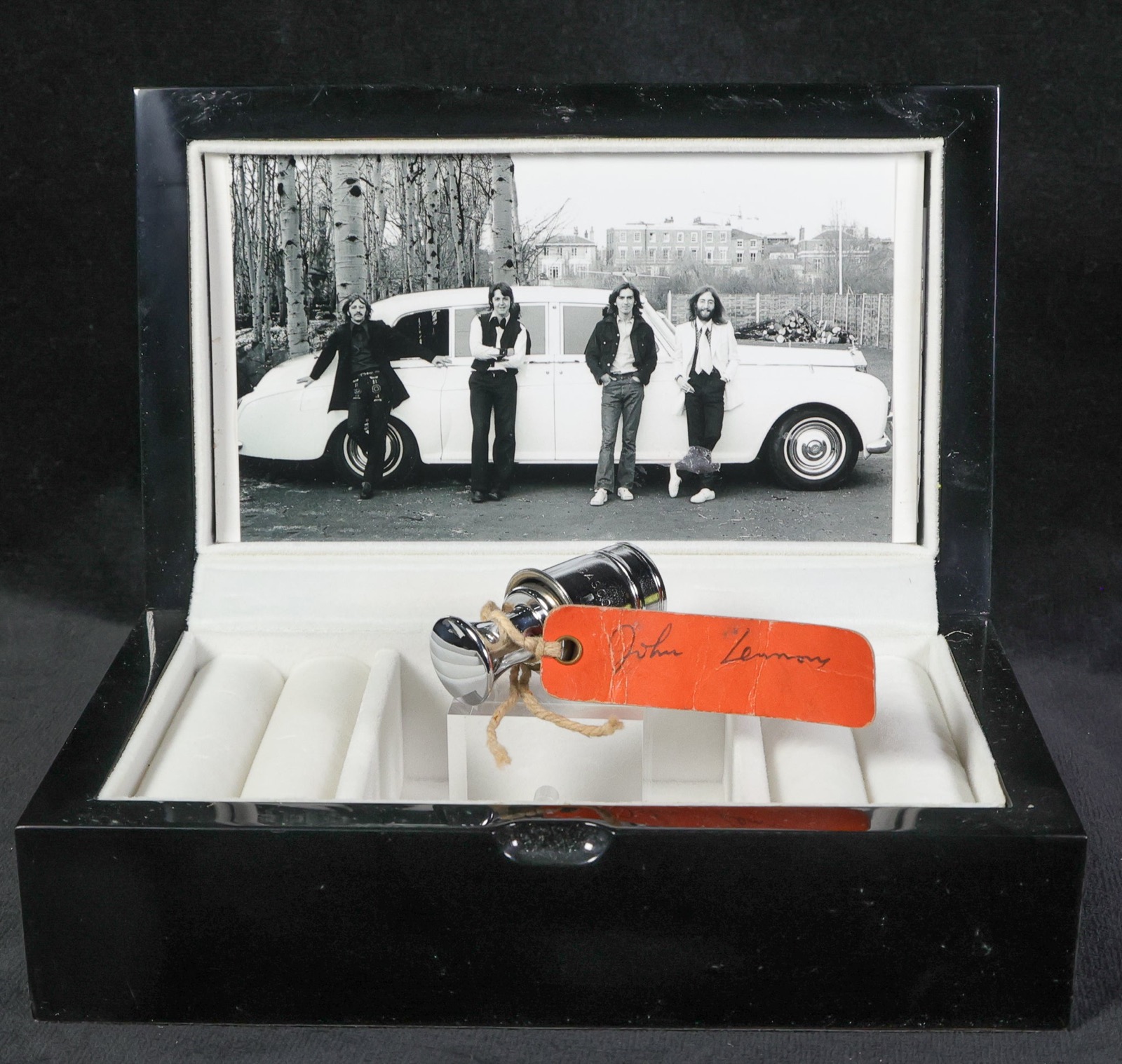 The lighter in its box, beneath a print of the white Rolls-Royce